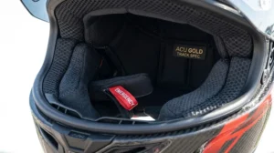The interior of a racing helmet showing the moisture-wicking lining and emergency release cheek pads for track safety.