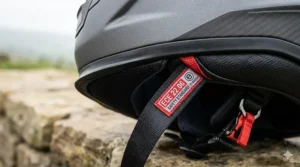 Alt text for image 2: Close-up of the ECE 22.06 safety standard label on a helmet chin strap, the legal requirement for motorcyclists on UK roads.