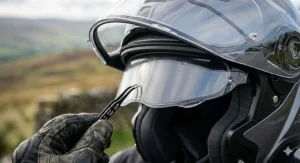 A clear Pinlock 120 anti-fog lens insert being fitted to a helmet visor to prevent misting during cold, rainy British winters.