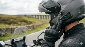 A motorcyclist wearing a dark modular helmet with an integrated Bluetooth intercom system.