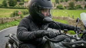 A detailed first-person perspective from inside a HUD motorcycle helmet, showing the projected navigation data and speed while approaching a country lane.