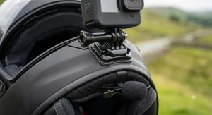 A detailed close-up of a black action camera securely attached to the chin bar mount of the Shoei motorcycle vlogging helmet.