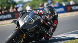 A professional rider wearing a sleek full carbon race helmet during a track day at a circuit.