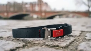 A close-up of the micrometric chin strap buckle and red release tab, resting on the damp London cobblestones.