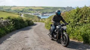 Motorcyclist riding on a UK road wearing a helmet with a stylish mirror tinted visor.
