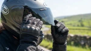 Close-up of a rider adjusting a dark smoke-tinted visor to minimise sun glare during daytime motorway riding.