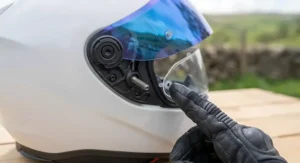 Installing a Pinlock anti-fog insert onto the interior pins of a blue mirror helmet visor.