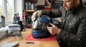 Motorcyclist installing a new replacement mirrored visor onto a full-face helmet in a workshop.