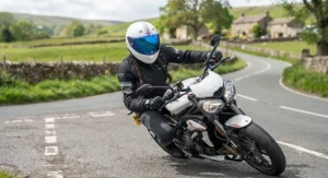 Motorcyclist wearing a helmet with a blue mirror visor riding on a sunny day in the UK.