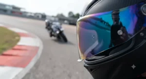 Close-up of a tinted mirror visor attached to a racing motorcycle helmet, showing the reflective outer coating for bright track conditions.