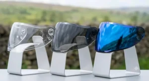 Side-by-side comparison of clear, tinted, and blue mirror helmet visors showing different light transmission levels.